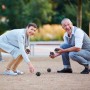 Zwei Personen spielen Boule mit schwarzem Relaxdays Boule Kugeln Set im Freien.