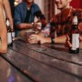 Brauner Relaxdays Flachmann aus Edelstahl mit Kunstlederhülle auf Holztisch, von Hand gehalten. Für Camping & Outdoor.