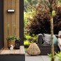 Philips Stratosphere LED Aussenwandleuchte in Szene gesetzt mit Sitzbereich im Garten.