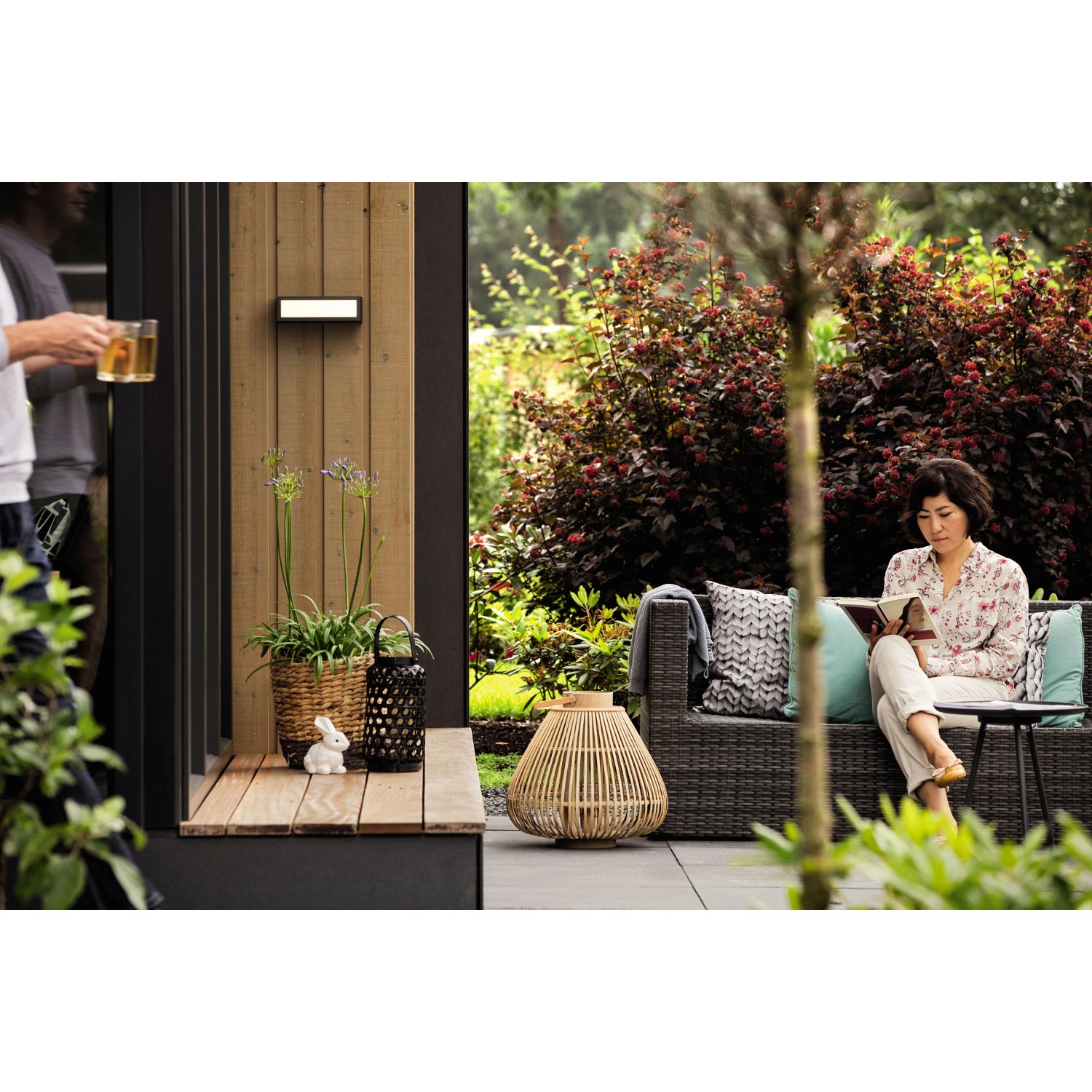 Philips Stratosphere LED Aussenwandleuchte in Szene gesetzt mit Sitzbereich im Garten.