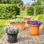 Florus Pflanztöpfe Sienna in Terrakotta und Anthrazit mit bunten Blumen auf einer Terrasse.