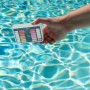 Bayrol Pooltester pH/Cl mit Farbskala zur Poolwasseranalyse in der Hand über Wasser.