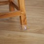 Stuhlbein mit transparenten Relaxdays Stuhlbeinkappen mit Filzgleiter auf Holzboden.