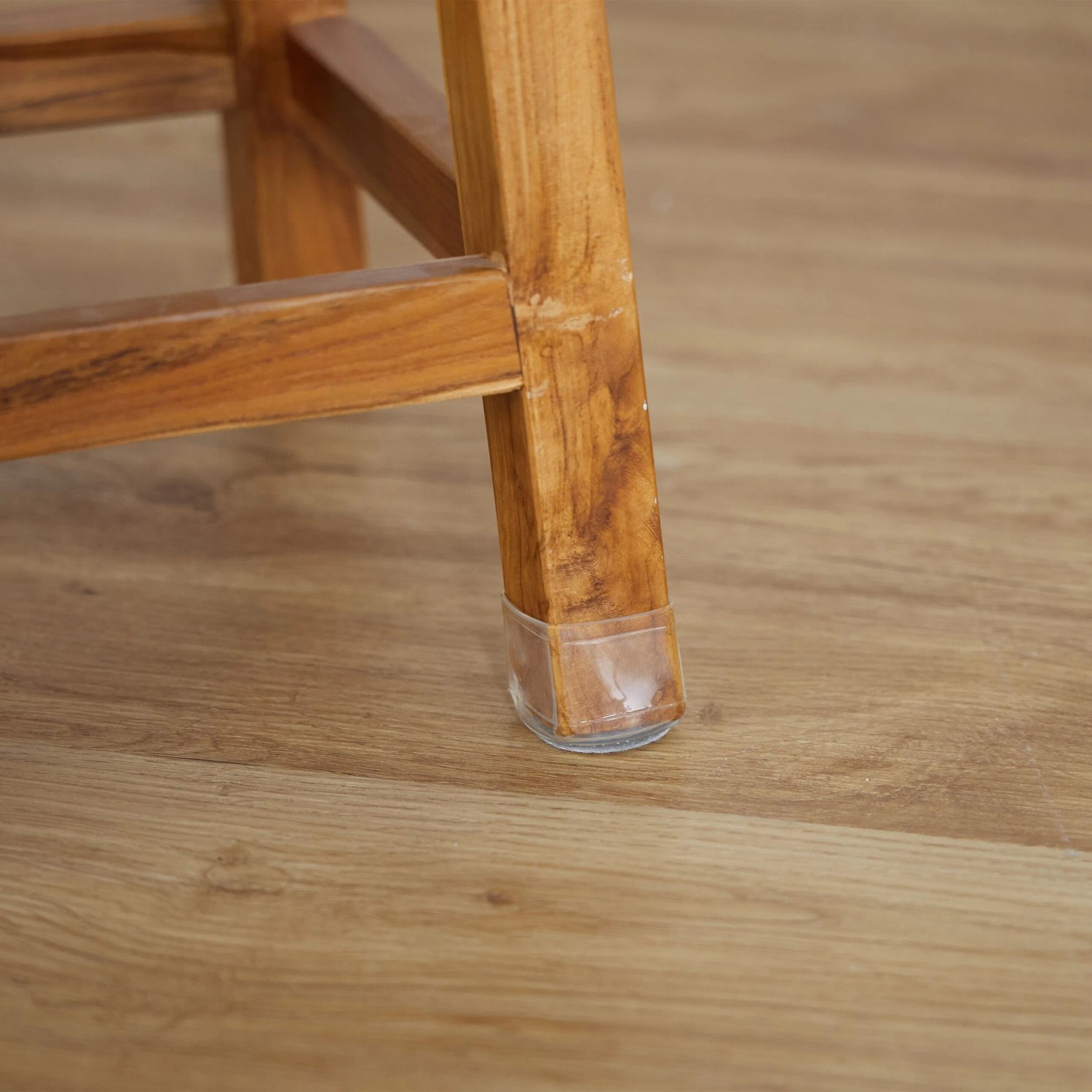 Stuhlbein mit transparenten Relaxdays Stuhlbeinkappen mit Filzgleiter auf Holzboden.