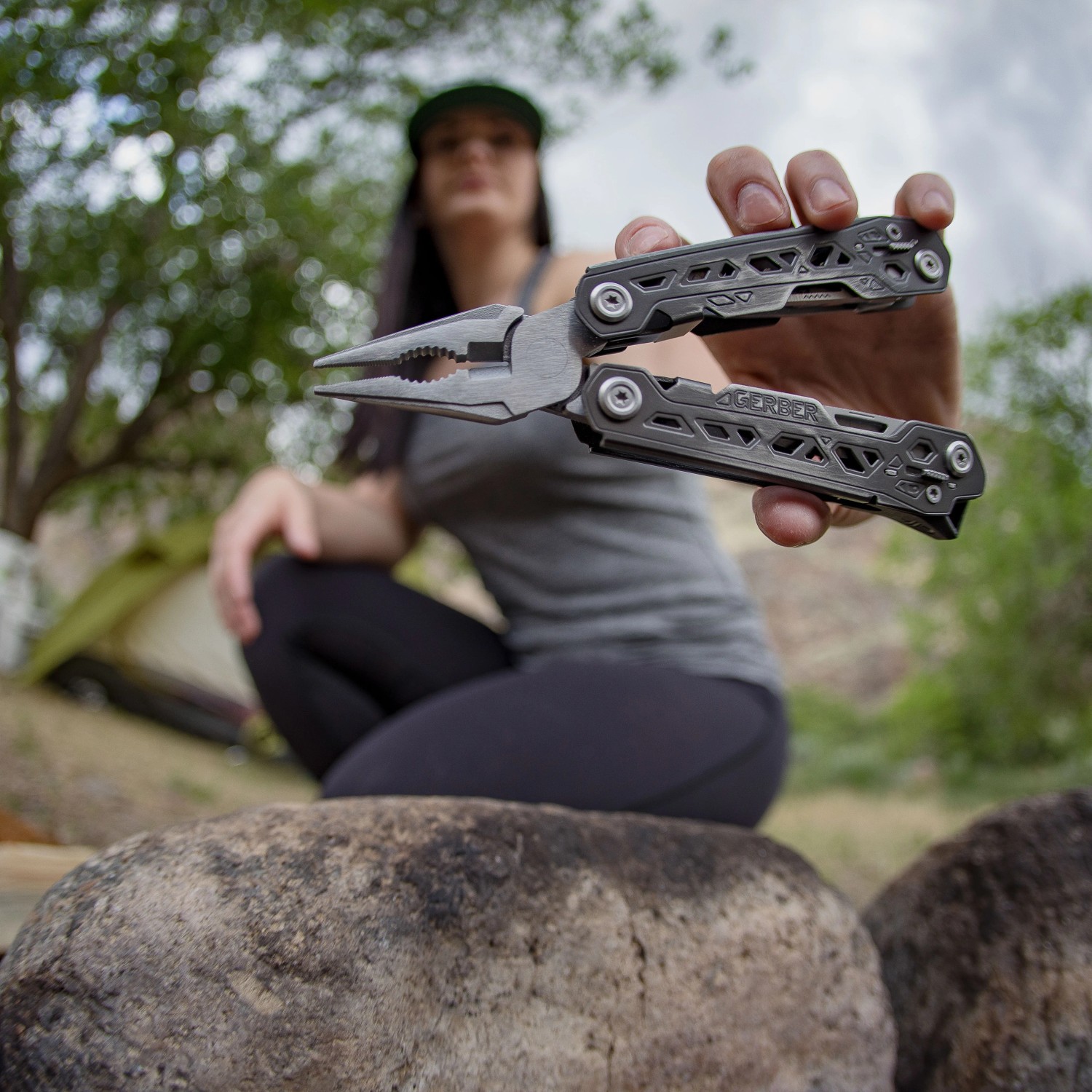 Gerber Multi-Tool Truss mit 17 Werkzeugen, gehalten vor einer Frau beim Camping.