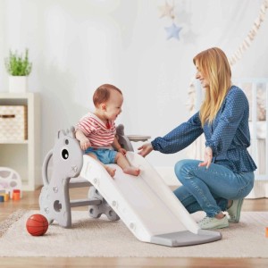 Graue AIYAPLAY Kinderrutsche mit Giraffen-Design und Basketballkorb. Lächelndes Kind (1-3 Jahre) rutscht, Frau assistiert.