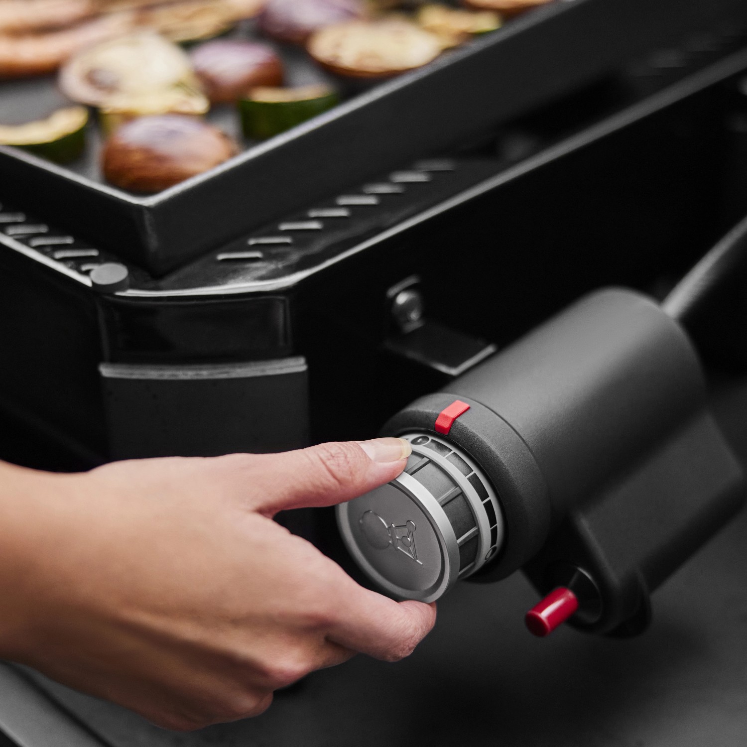 Weber Slate GP 43cm Premium Plancha Gasgrill mit Hand am Bedienknopf.