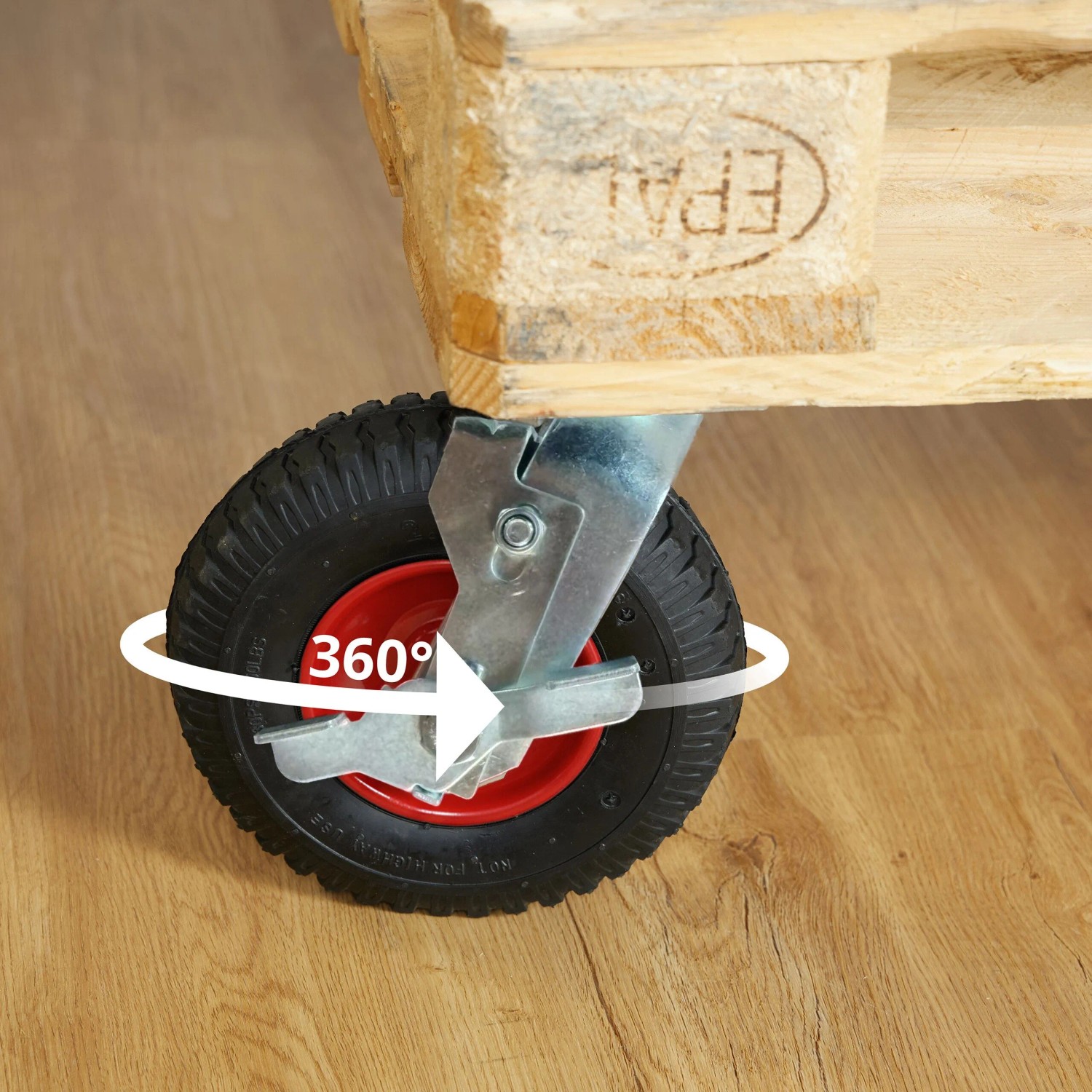 Schwarze luftbereifte Lenkrolle mit roter Nabe, 360° drehbar, an Holzpalette. Schwerlast-Transportrolle mit Bremse.