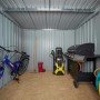 Innenansicht: Pergart Gerätehaus Lübeck 88, anthrazit, mit Gartengeräten wie Fahrrad, Grill und Hochdruckreiniger.