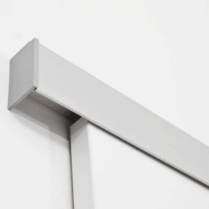 Weiße Holzschiebetür mit grauer Aluminium-Laufschiene, wandmontiert. Detail des oberen Türblatts.