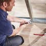 Mann crimpt Metallprofile mit wolfcraft Profil-Verbindungszange auf Holzboden. Schnelle, dauerhafte Verbindung für Trockenbau.