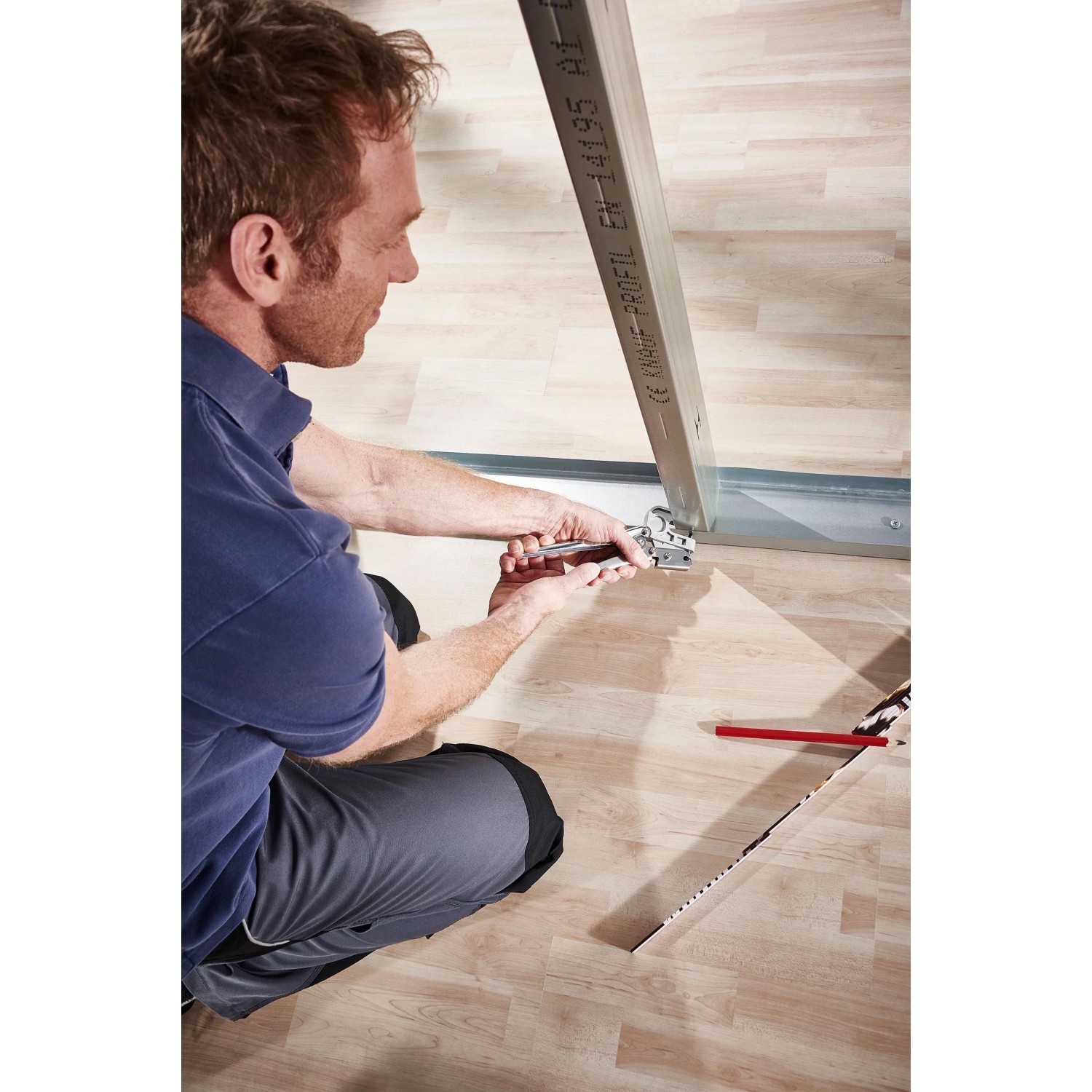 Mann crimpt Metallprofile mit wolfcraft Profil-Verbindungszange auf Holzboden. Schnelle, dauerhafte Verbindung für Trockenbau.