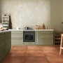 Küche mit Bodenfliese Feinsteinzeug Milano Cotto 80x80 cm in Cotto-Optik und grünen Küchenmöbeln.