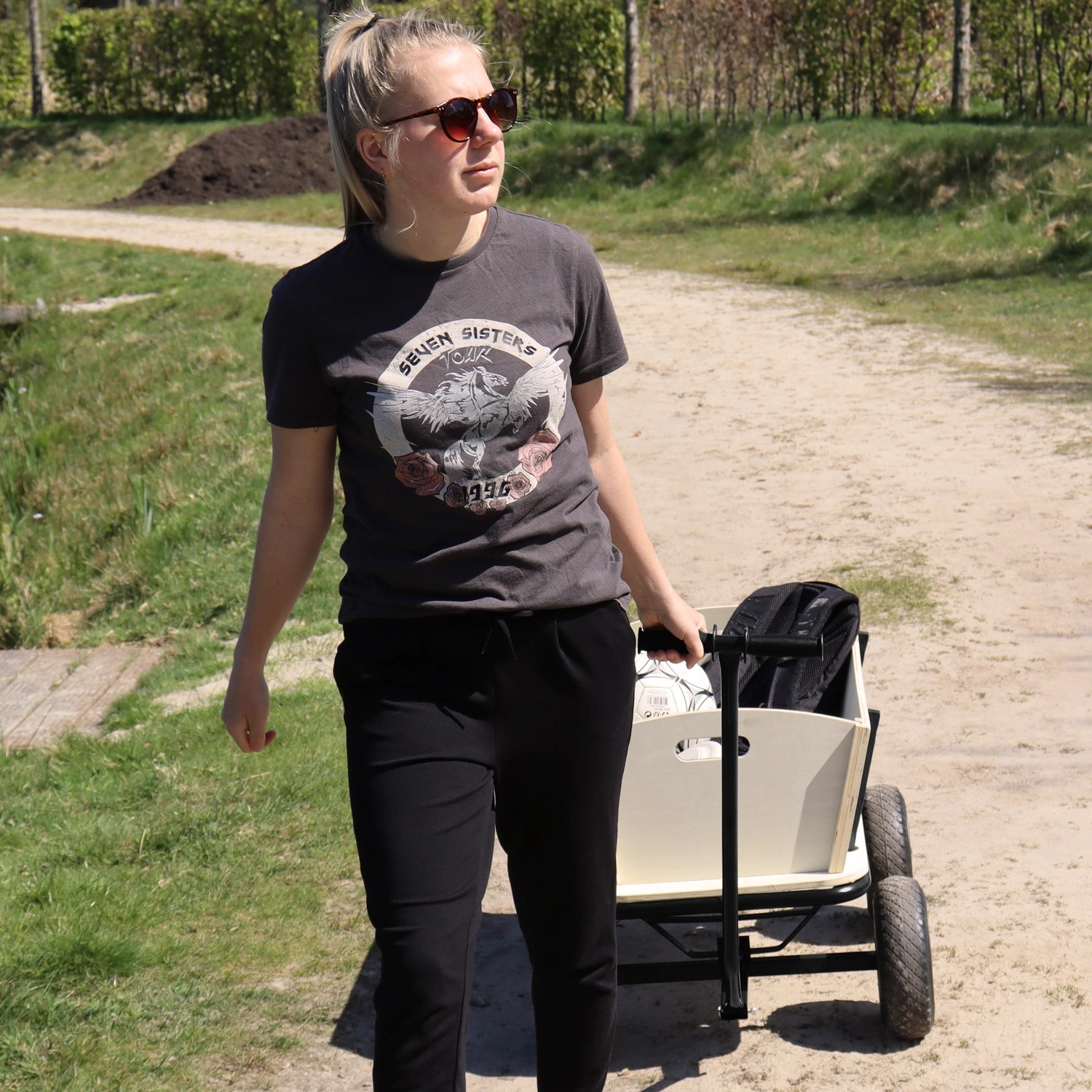 Schwarzer Sunny Bollerwagen Billy Beach Wagon mit Frau auf einem Weg.