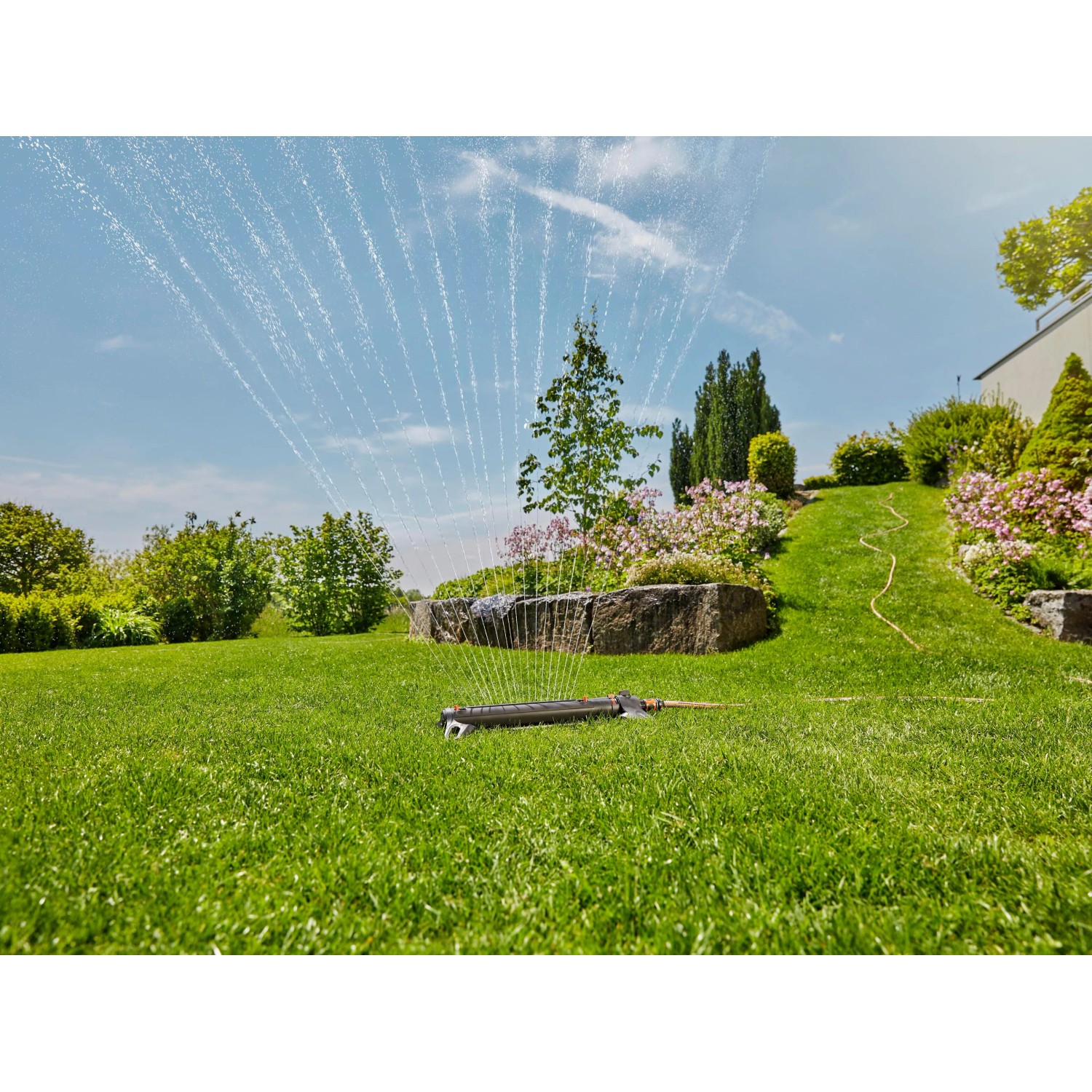Gardena Viereckregner AquaZoom L in Aktion: Bewässerung eines grünen Gartens.