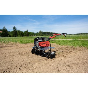 Al-Ko MH 1150 Comfort Benzin-Motorhacke mit rotem Gehäuse und schwarzen Hackmessern auf Ackerboden.