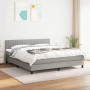 Hellgraues Boxspringbett 180x200 cm mit Matratze und Kopfteil im Schlafzimmer.