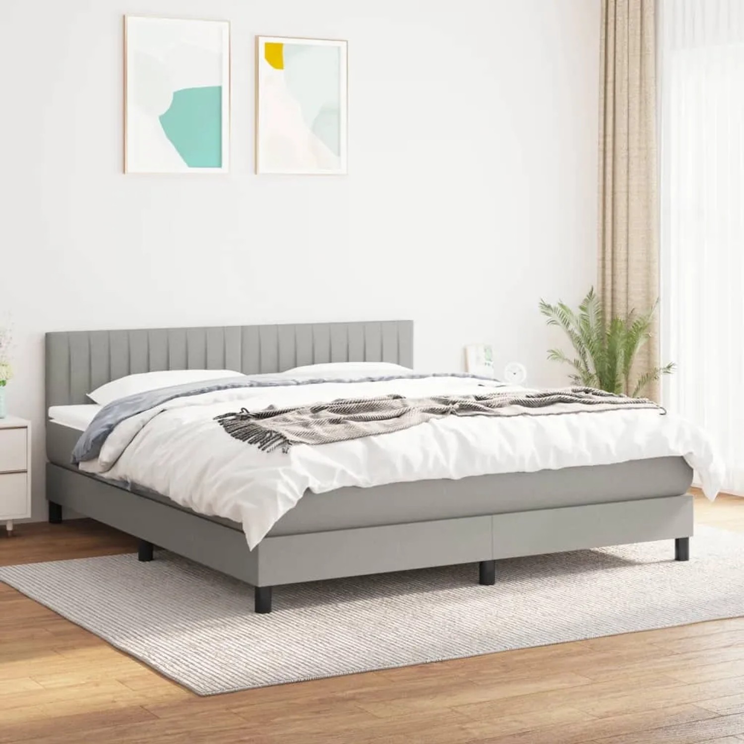 Hellgraues Boxspringbett 180x200 cm mit Matratze und Kopfteil im Schlafzimmer.