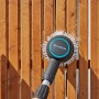 Gardena Akku-Multi-Reiniger AquaBrush Patio im Einsatz an einem Holzzaun.