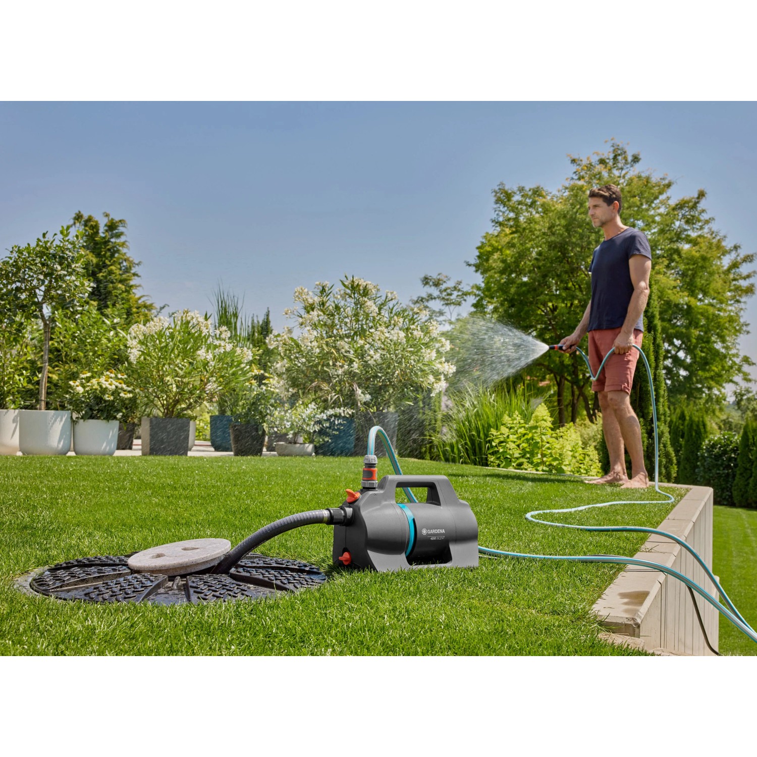 Gardena Gartenpumpe 4200 Silent Set im Einsatz: Mann bewässert Garten mit der leisen Gartenpumpe.