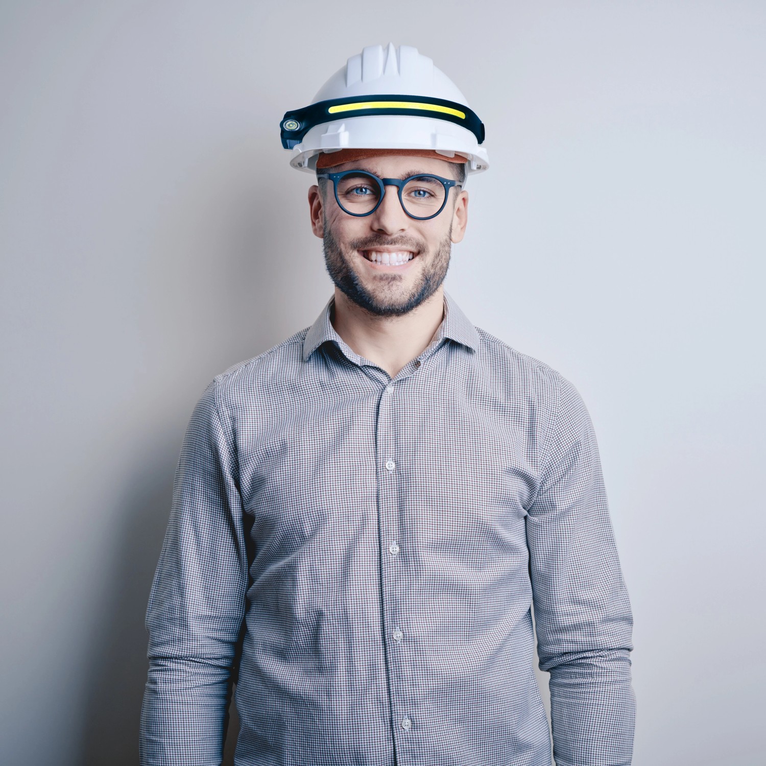 Mann mit weißem Schutzhelm und LED Stirnlampe mit Gestensteuerung. Taschenlampe für Handwerker.