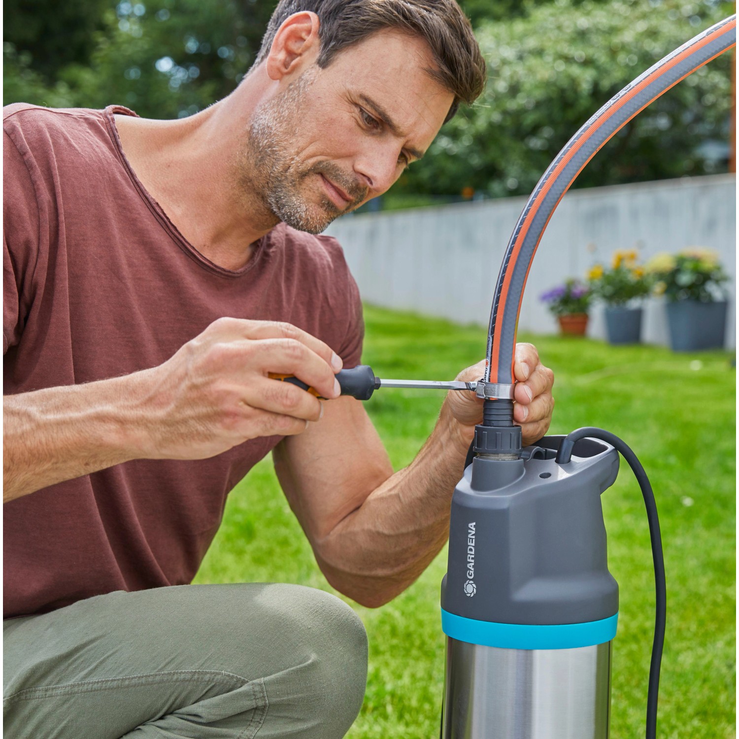 Mann montiert Gardena Tauch-Druckpumpe 5900/4 inox automatic im Garten.