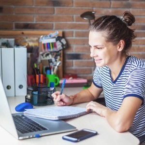 Frau schreibt am Schreibtisch mit Relaxdays Stiftehalter Anthrazit im Hintergrund.