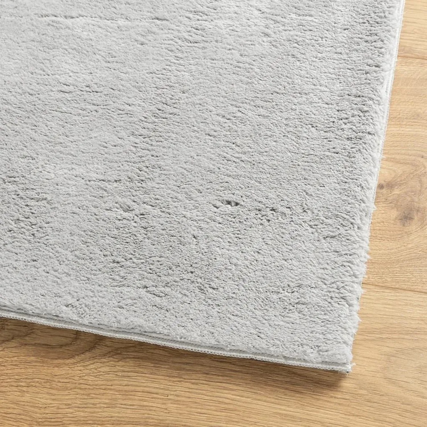 Grauer, weicher Kurzflor-Teppich HUARTE (80x250 cm) auf Holzfußboden. Flauschige Textur, waschbar.