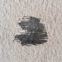 Bohloch mit dunklem Untergrund in heller Wand, repariert mit Fischer Reparaturspachtel.