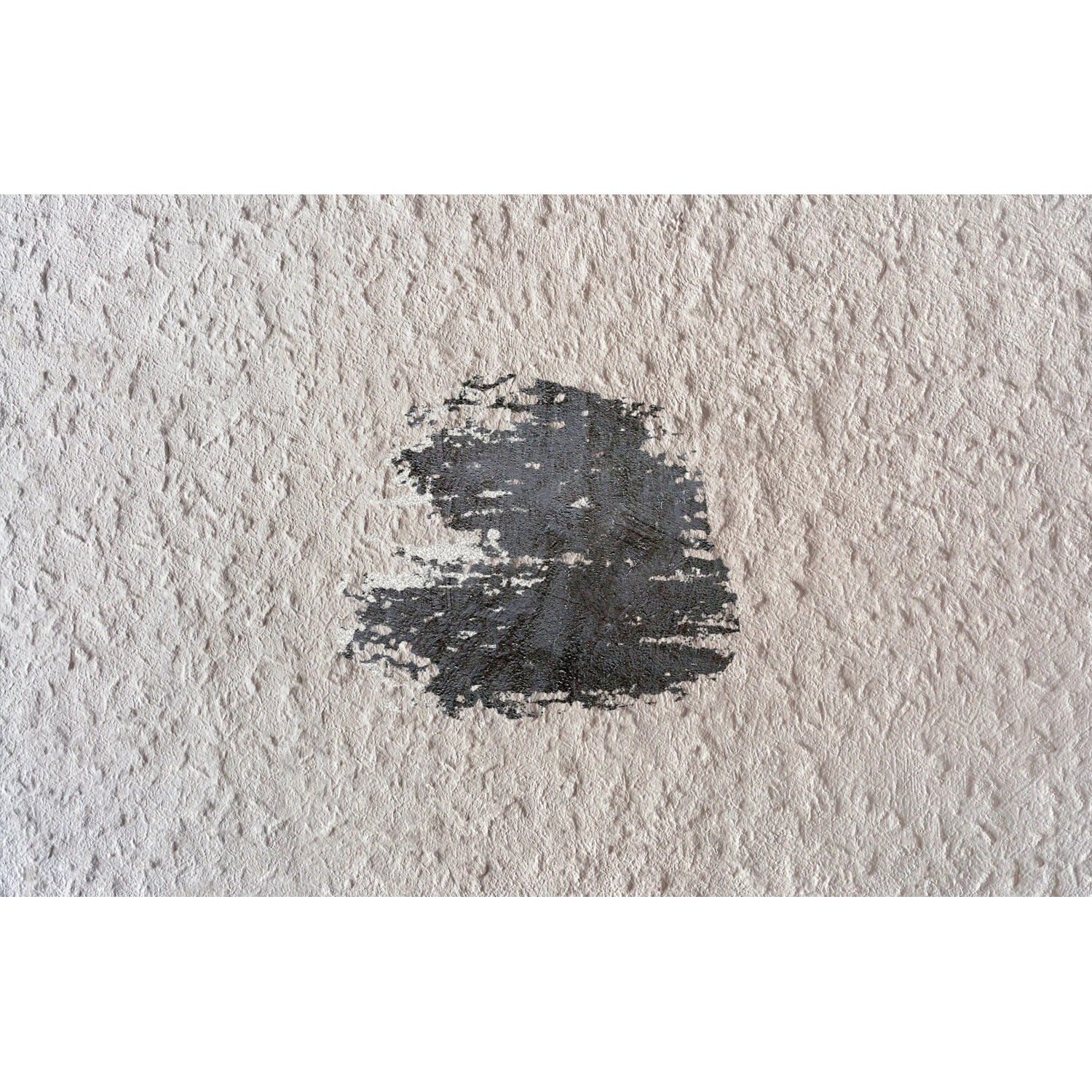 Bohloch mit dunklem Untergrund in heller Wand, repariert mit Fischer Reparaturspachtel.