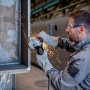 Mann schleift Metall mit dem Bosch Professional GWX 17-125 PSB Winkelschleifer, Funken fliegen.