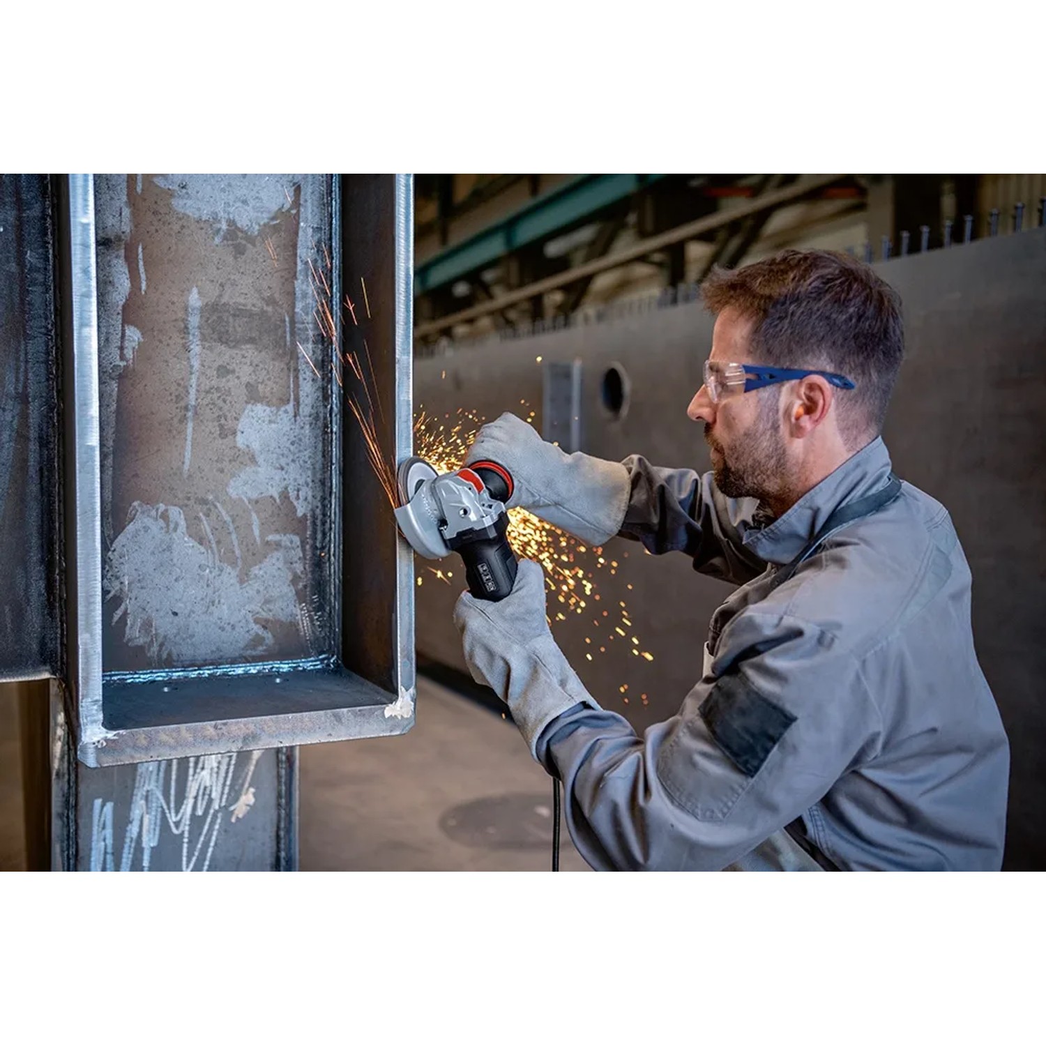 Mann schleift Metall mit dem Bosch Professional GWX 17-125 PSB Winkelschleifer, Funken fliegen.