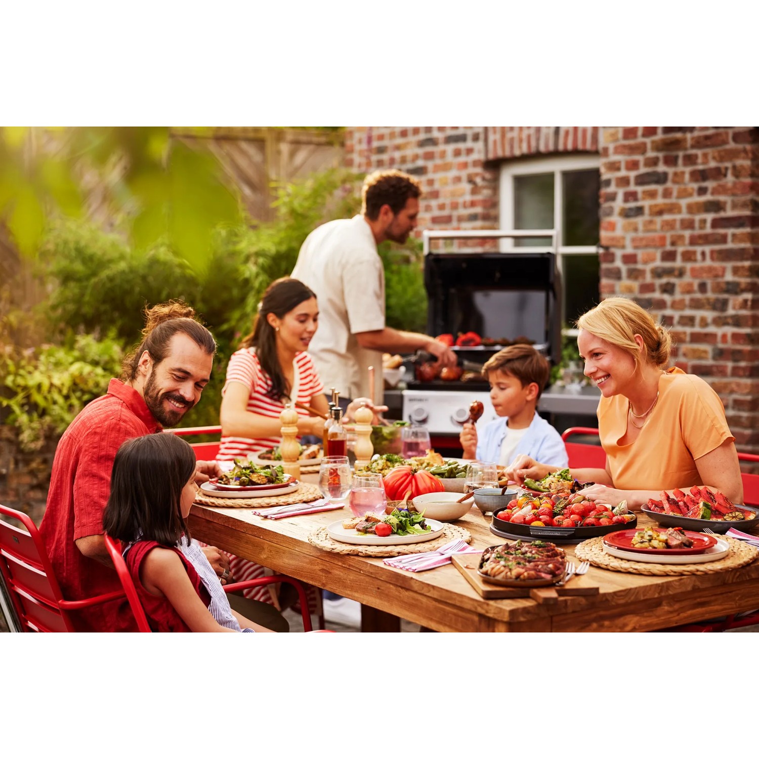 Familie grillt mit Weber Gasgrill E-410 Spirit Schwarz. Grillparty im Garten.