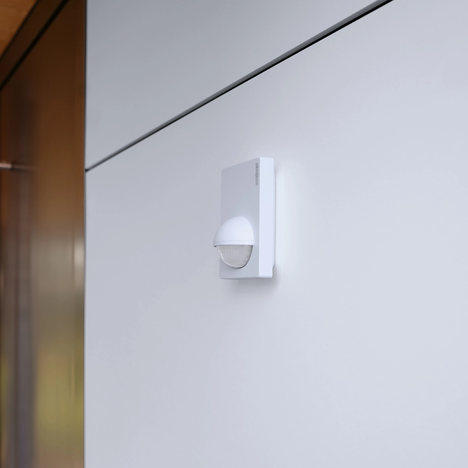 Weißer Steinel Bewegungsmelder IS 180-2 an Wand montiert, Erfassungswinkel 180 Grad.