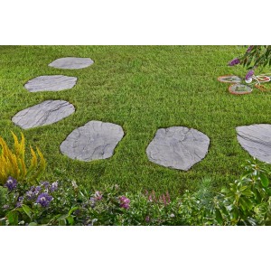 Grau-nuancierte Trittplatten Nativa in Natursteinoptik auf Rasen und zwischen Blumen im Garten.