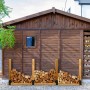 Schwarze Stahl Holzstapelhilfen für ein Brennholzregal vor Holzhütte. Ideal zur Kaminholz-Lagerung.