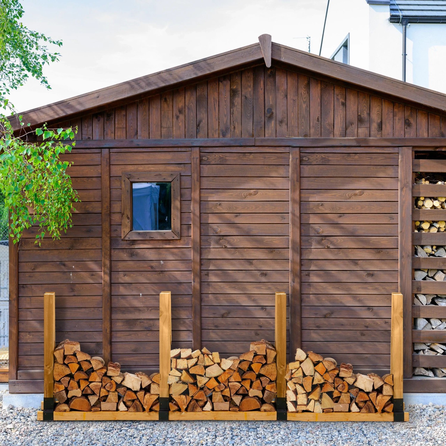 Schwarze Stahl Holzstapelhilfen für ein Brennholzregal vor Holzhütte. Ideal zur Kaminholz-Lagerung.