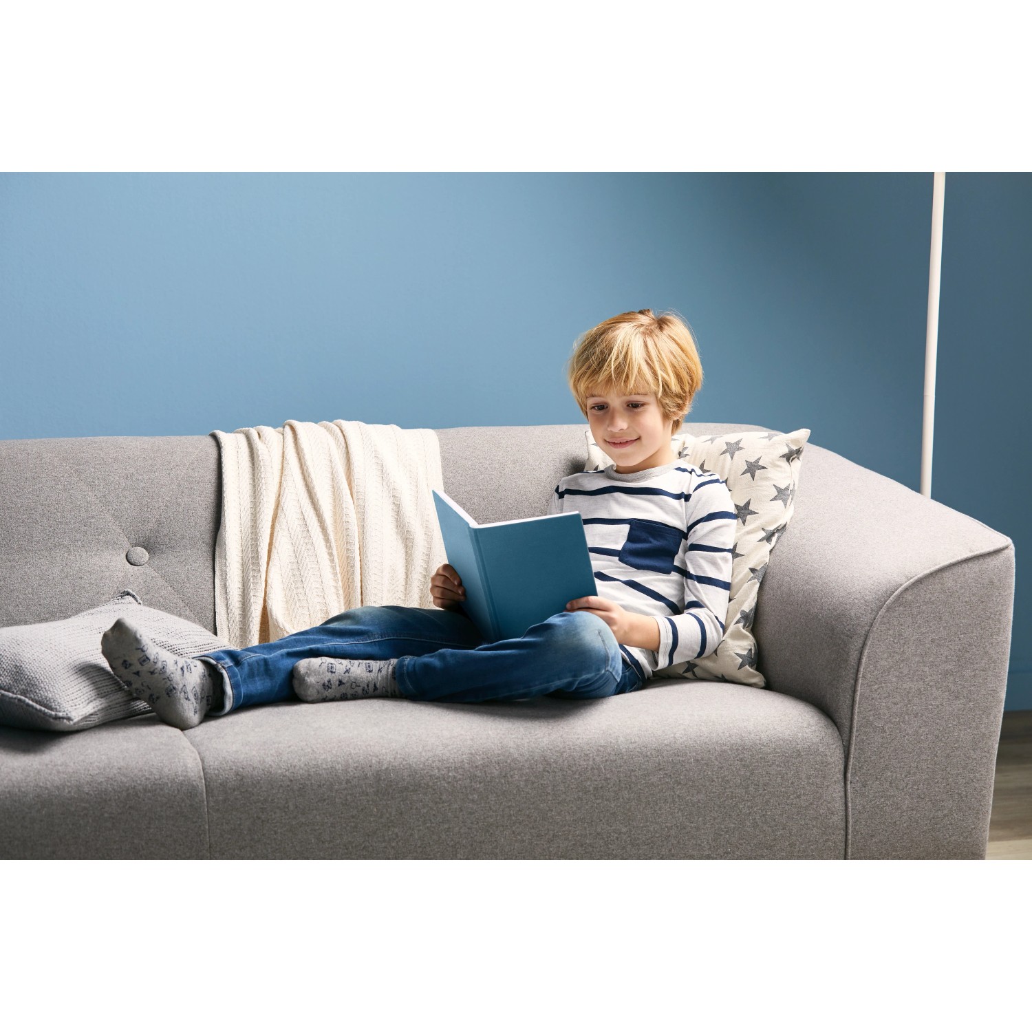 Philips GU10 LED-Leuchtmittel, 4,6W, neutralweiß, auf grauem Sofa mit lesendem Kind.