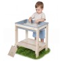 Kleinkind spielt mit Sand am roba Outdoor Spiel- & Wassertisch aus hellem Holz mit grauer Wanne auf Gras.
