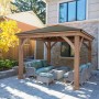 Westmann Holz Pavillon Devon 366x366 cm mit Aluminiumdach und Sitzgruppe im Garten.
