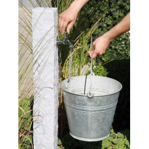 Arves Wasserzapfstelle Natura Granit: Wasserhahn befüllt Eimer im Garten.