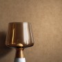 Goldene Newroom Vliestapete Zeno mit Textilstruktur als Hintergrund für eine Lampe.
