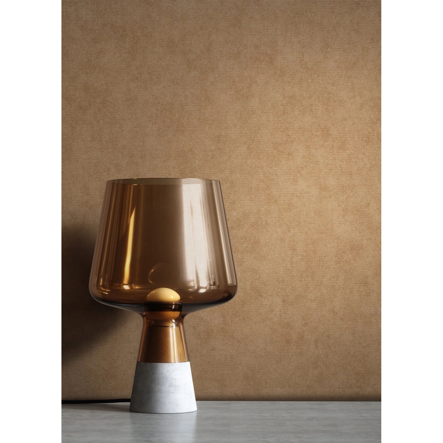 Goldene Newroom Vliestapete Zeno mit Textilstruktur als Hintergrund für eine Lampe.