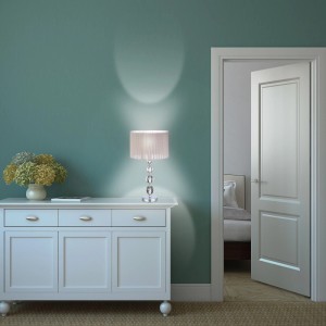 Nachttischlampe mit Stoffschirm und Kristallglas-Elementen auf weißer Kommode.