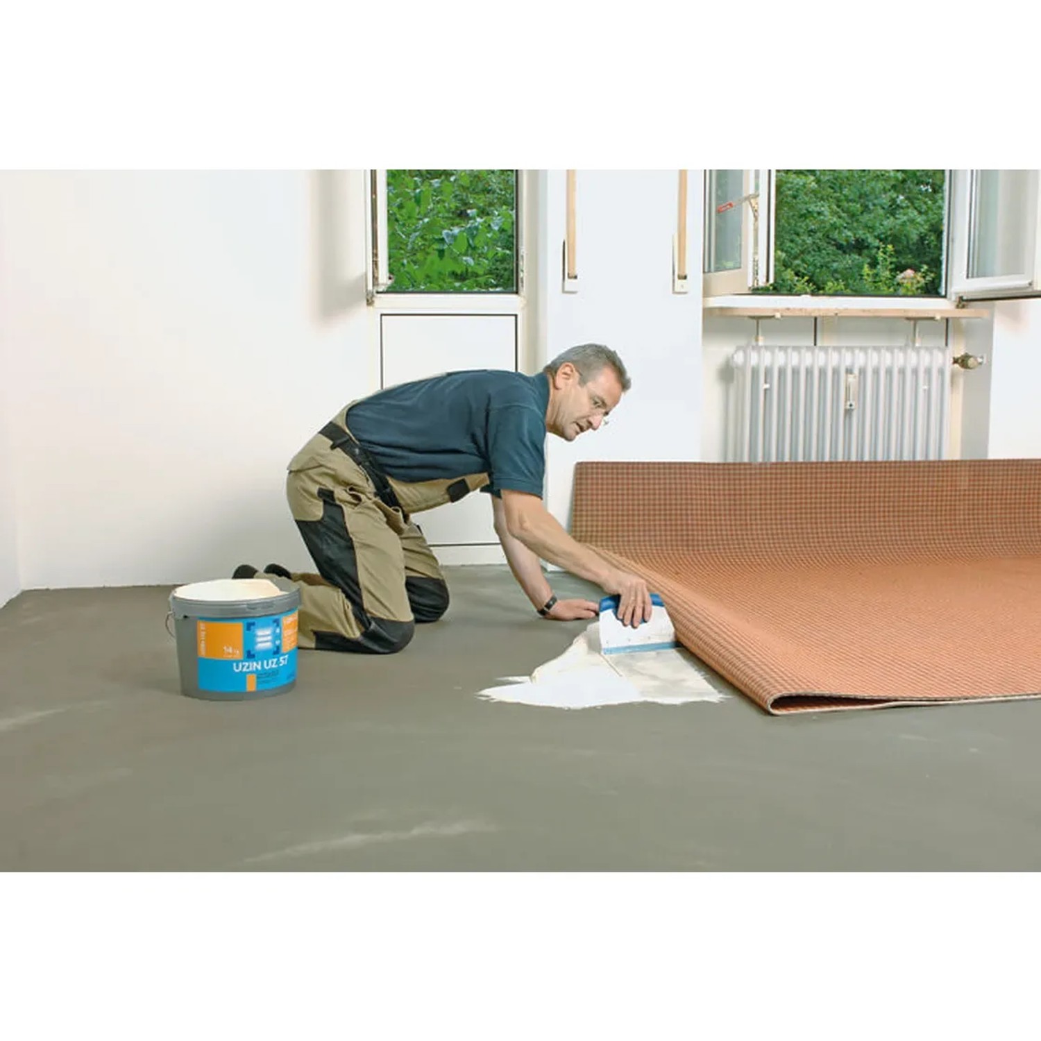 Handwerker verlegt Textilboden mit Uzin UZ 57 Klebstoff. Zubehör für Laminat & Parkett.