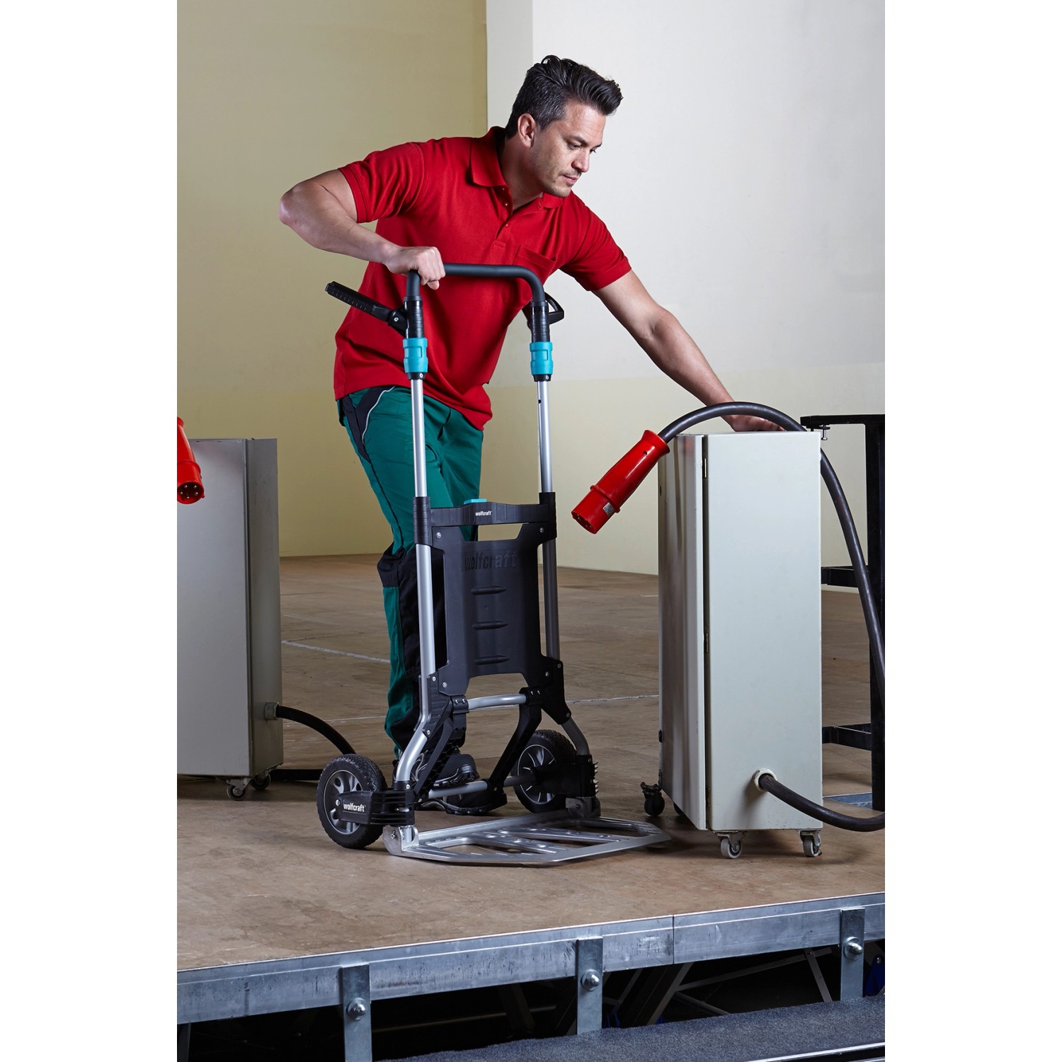 Mann nutzt wolfcraft Sackkarre TS 1500 zum Transport eines Geräts. Klappbare Baukarre mit großer Schaufel.