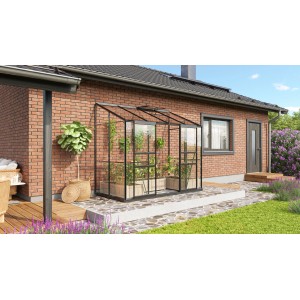 Vitavia Gewächshaus Ida 3300, schwarzes Anlehngewächshaus mit Pflanzen vor einer Backsteinwand.