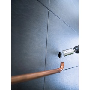 LUX Lochsäge Professional Ø 44 mm im Einsatz: Bohren eines Lochs in graue Fliesen für ein Kupferrohr.