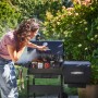 Frau grillt mit Char-Broil Holzkohlegrill Charcoal 2Go im Garten. Tragbarer Grill mit Ablage.