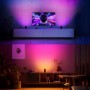 Philips Hue Play Wallwasher in Weiß, erzeugt farbiges Licht an der Wand hinter dem TV und auf einem Sideboard.
